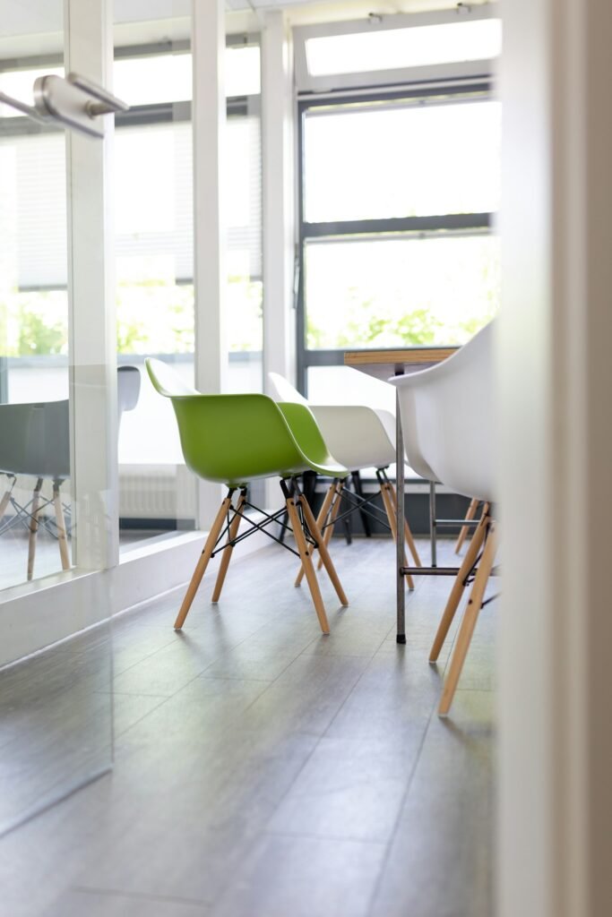 Green and white chairs beside tall windows in a bright meeting room